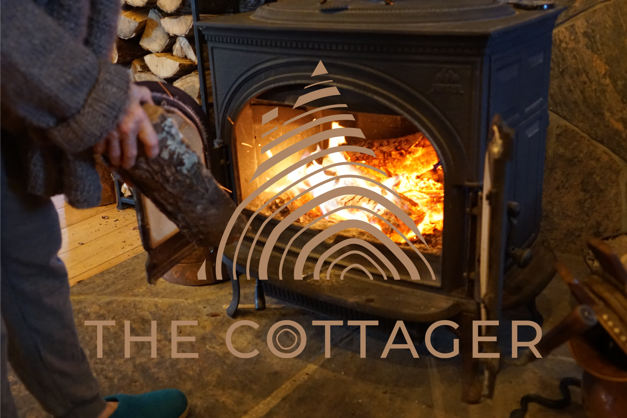 Person tending to a wood stove with 'The Cottager' branding.